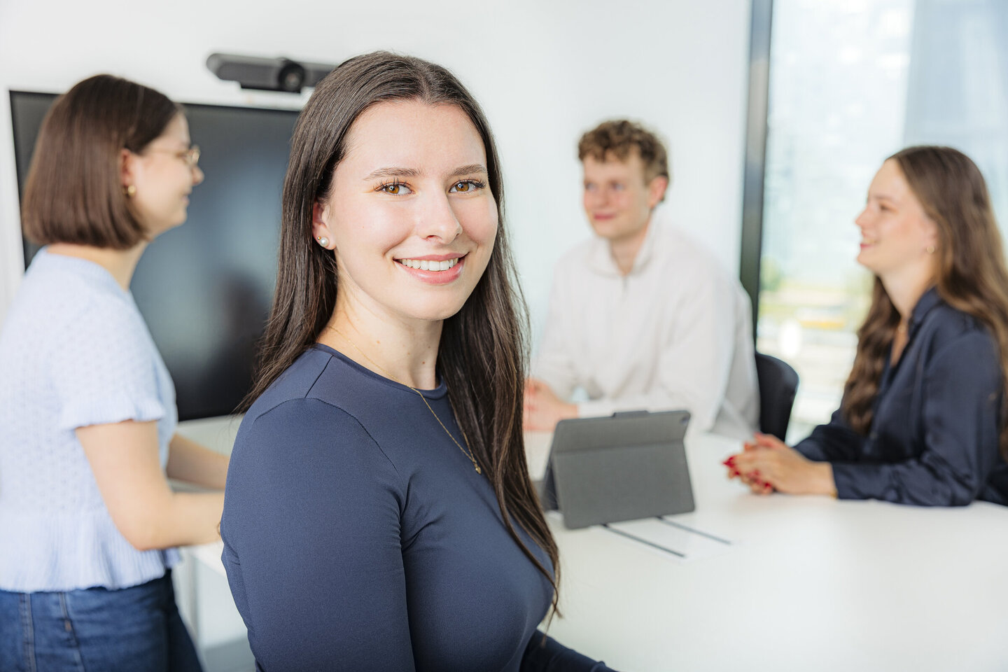4 Personen, die an einem Besprechungsraum-Tisch stehen